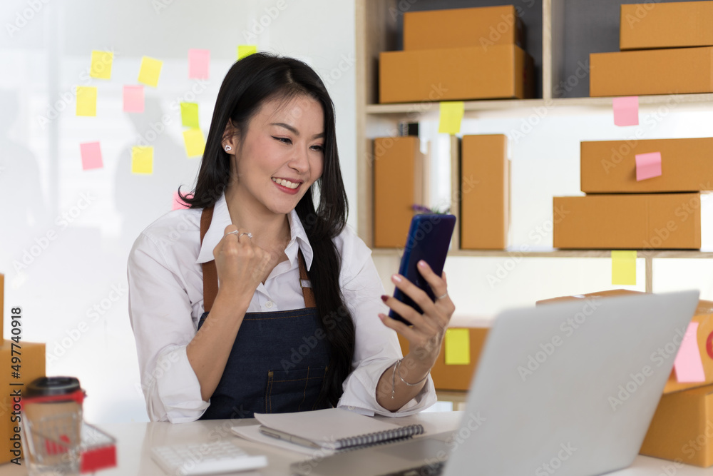 Happy Asian woman entrepreneur, Smile for sales success after checking order from online shopping st