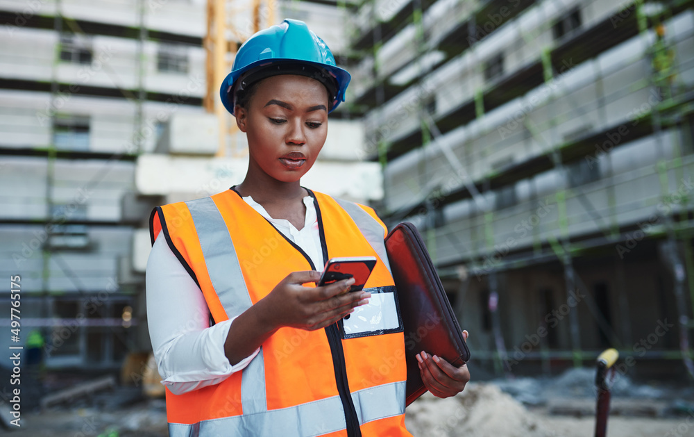 Forget the desk, use your phone. Shot of a young woman using a smartphone while working at a constru