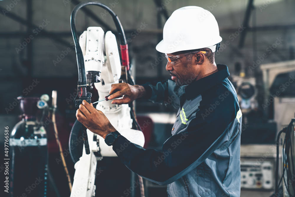 African American factory worker working with adept robotic arm in a workshop . Industry robot progra