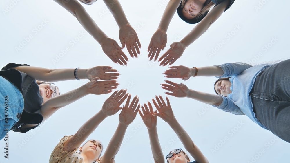 Girlfriends join the palms of their hands in the center making a circle shape.