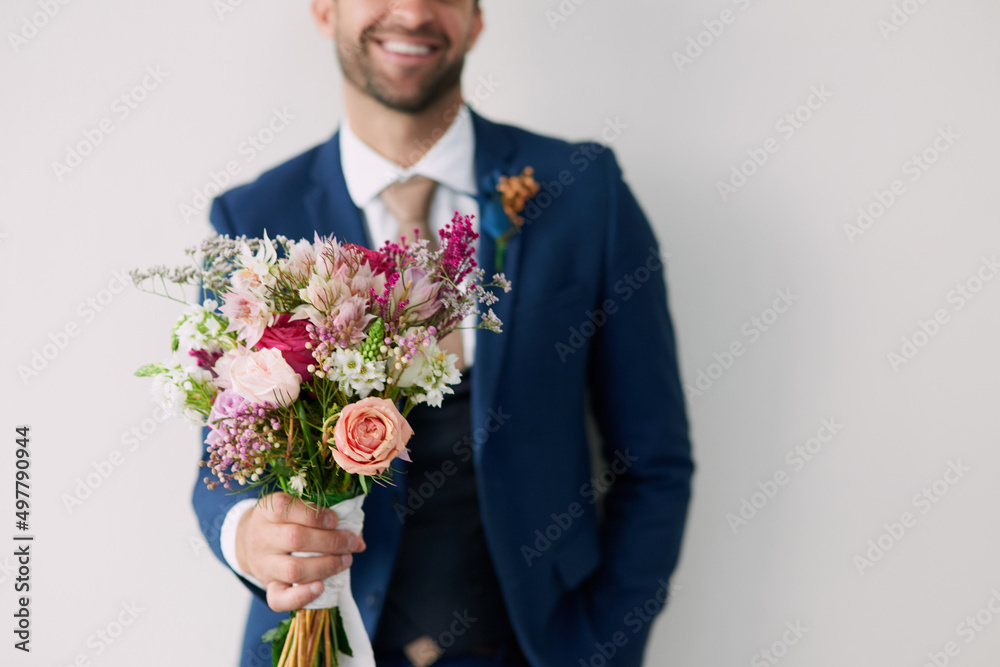 The flowers that won her heart. Studio shot of a handsome young groom holding a bunch of flowers a g