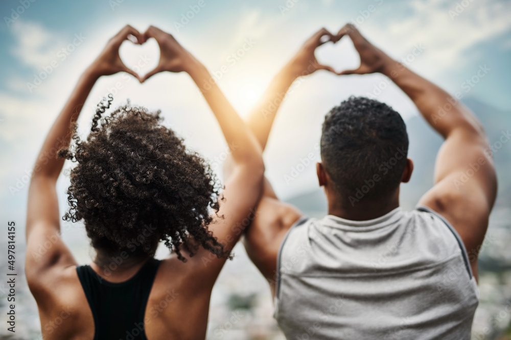 Happy hearts. Rearview shot of a sporty young couple making heart shapes with their hands while exer