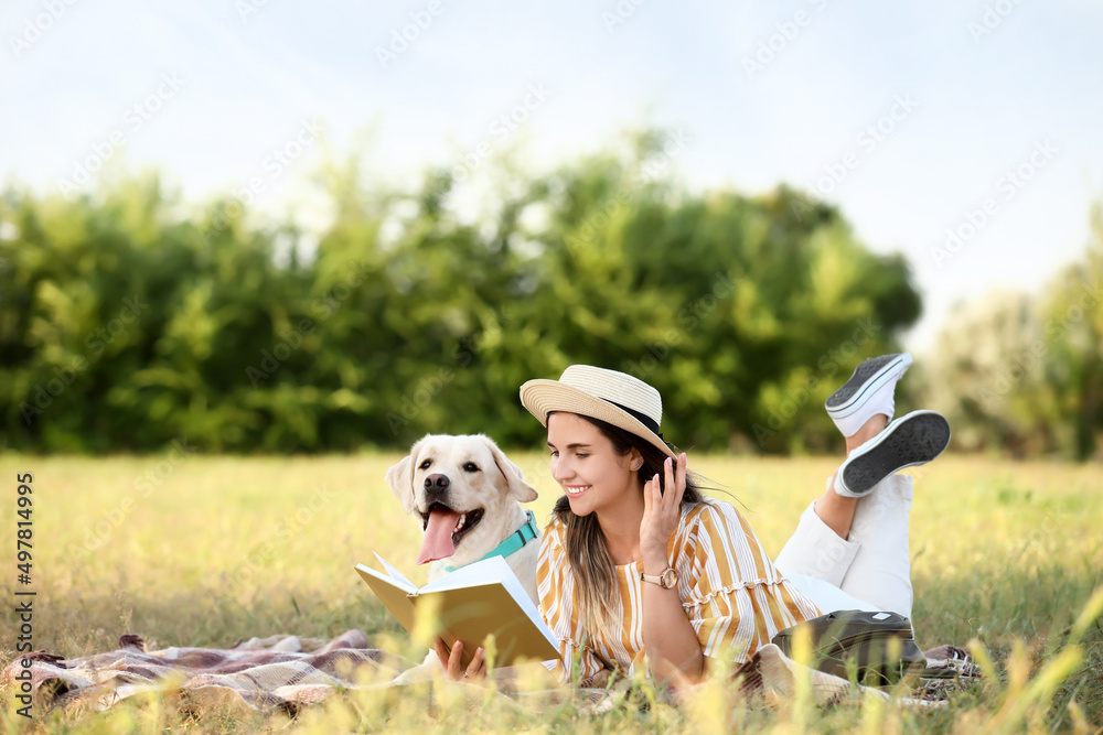 夏天，带着可爱拉布拉多的女人在户外看书