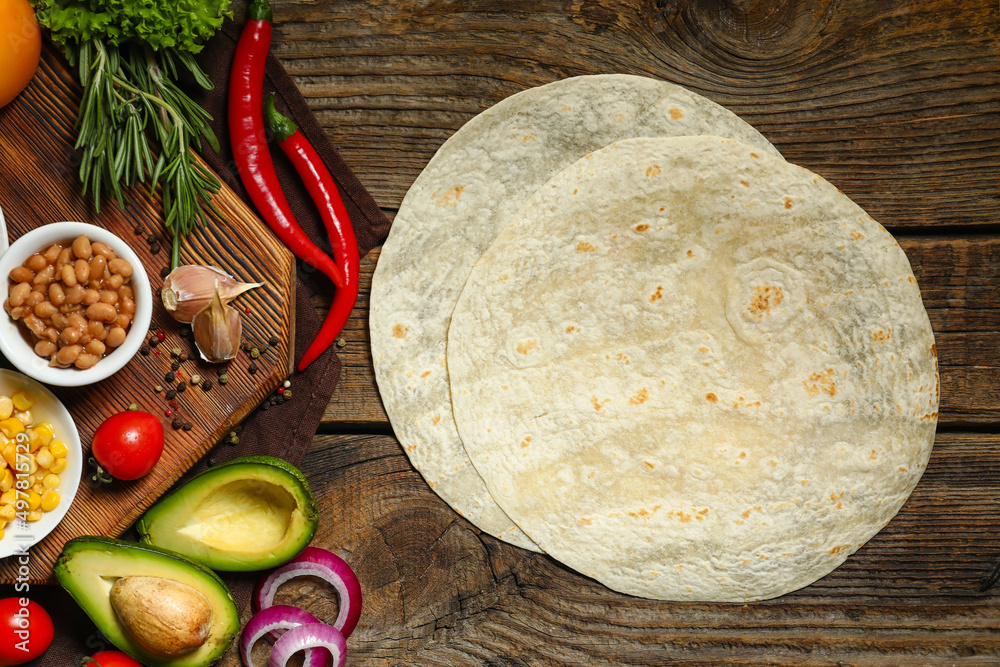 Tortillas and fresh vegetables for preparing burrito on wooden background