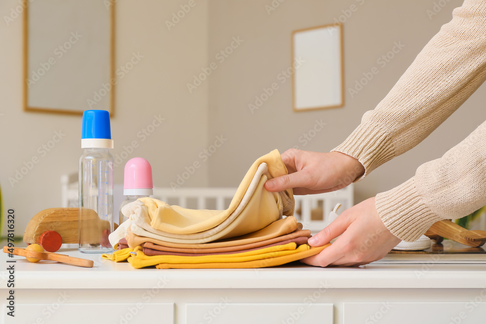 房间桌子上放着一叠婴儿衣服的女人，特写