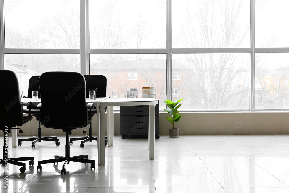 Table and chairs in interior of light conference hall with big window