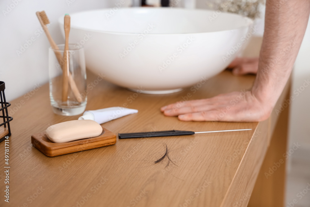 Fallen down hair of young man and comb on table in bathroom, closeup