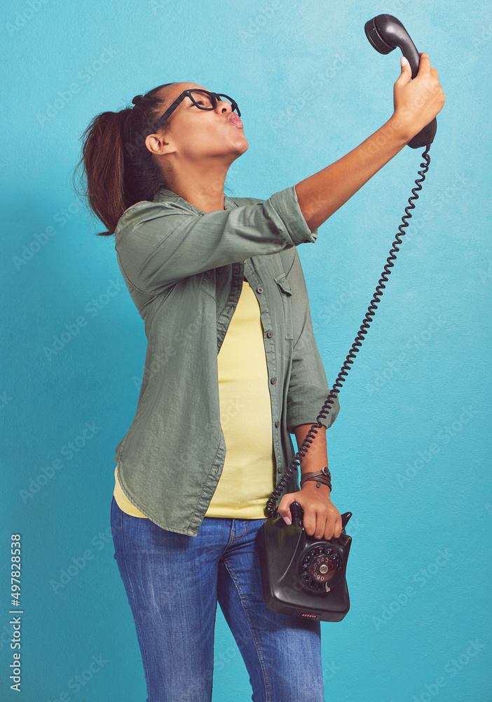 Lets do this the old-fashioned way. Shot of a young woman talking a selfie on an old fashioned telep