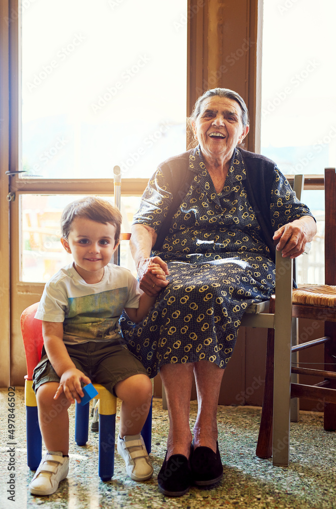 The youth and the wise. Portrait of a cheerful little boy sitting next his great grandmother while l