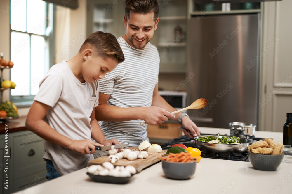 你真是太自然了。一个小男孩在厨房里帮父亲做饭的剪短镜头。