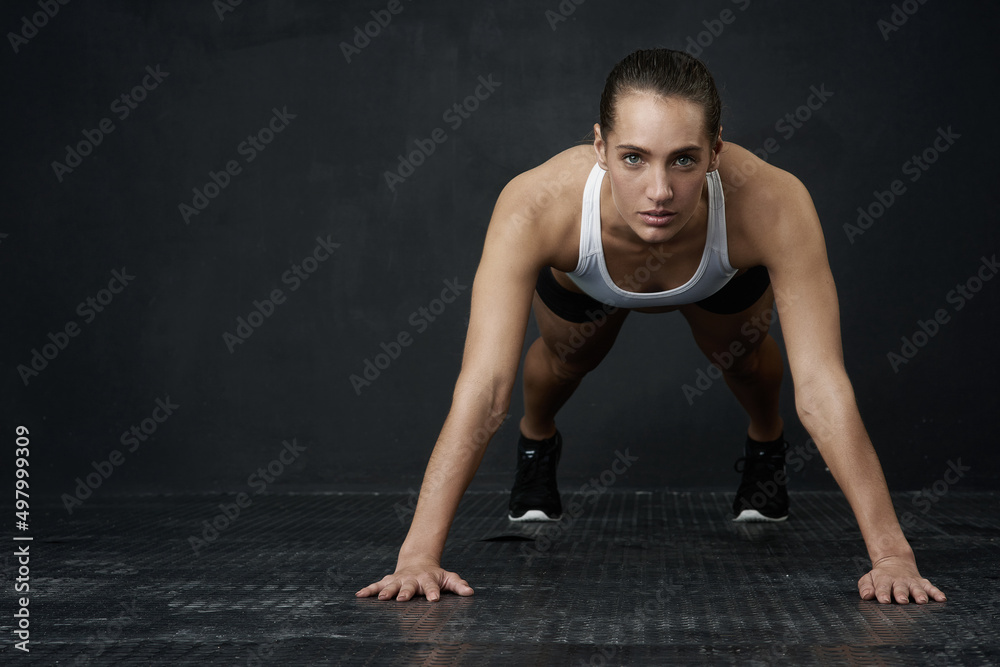 Its time to get ripped. Studio portrait of an attractive young woman working out against a dark back