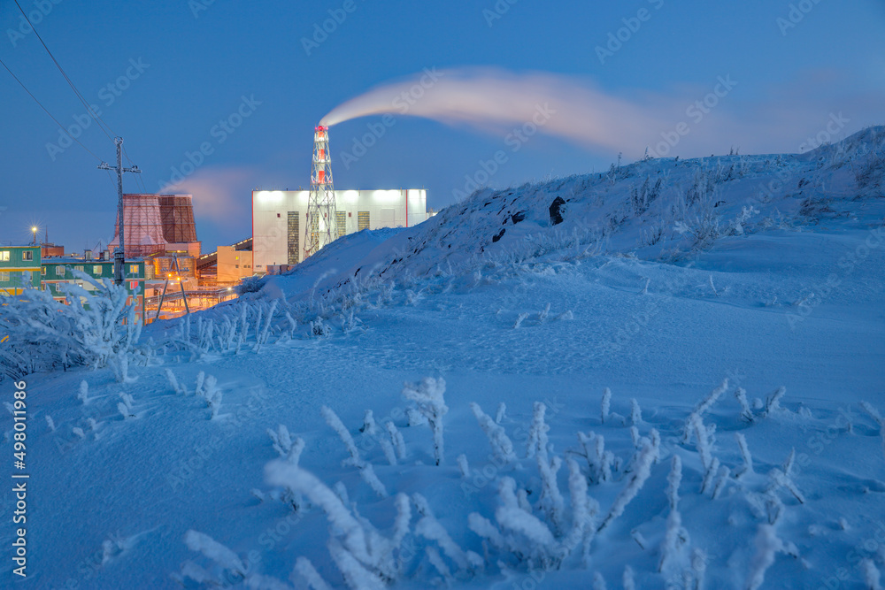 冬季北极工业景观。白雪皑皑的山坡和火电厂景观