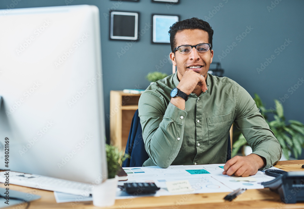 He calls the shots in the office. Portrait of a cheerful young businessman seated behind his desk bu