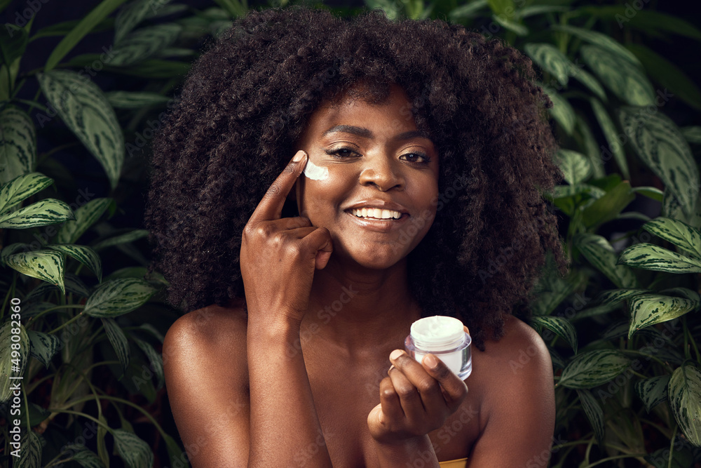 The less chemicals, the happier my skin. Shot of a beautiful young woman applying moisturiser to her