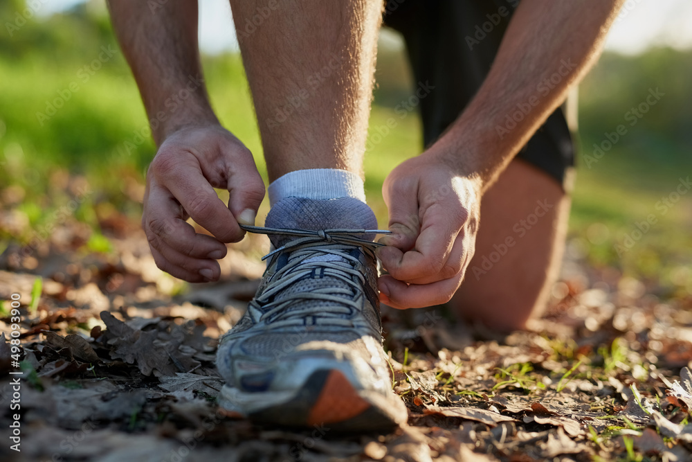 Laces first, workout second. Closeup shot on an unrecognizable male athlete tying his laces while ou