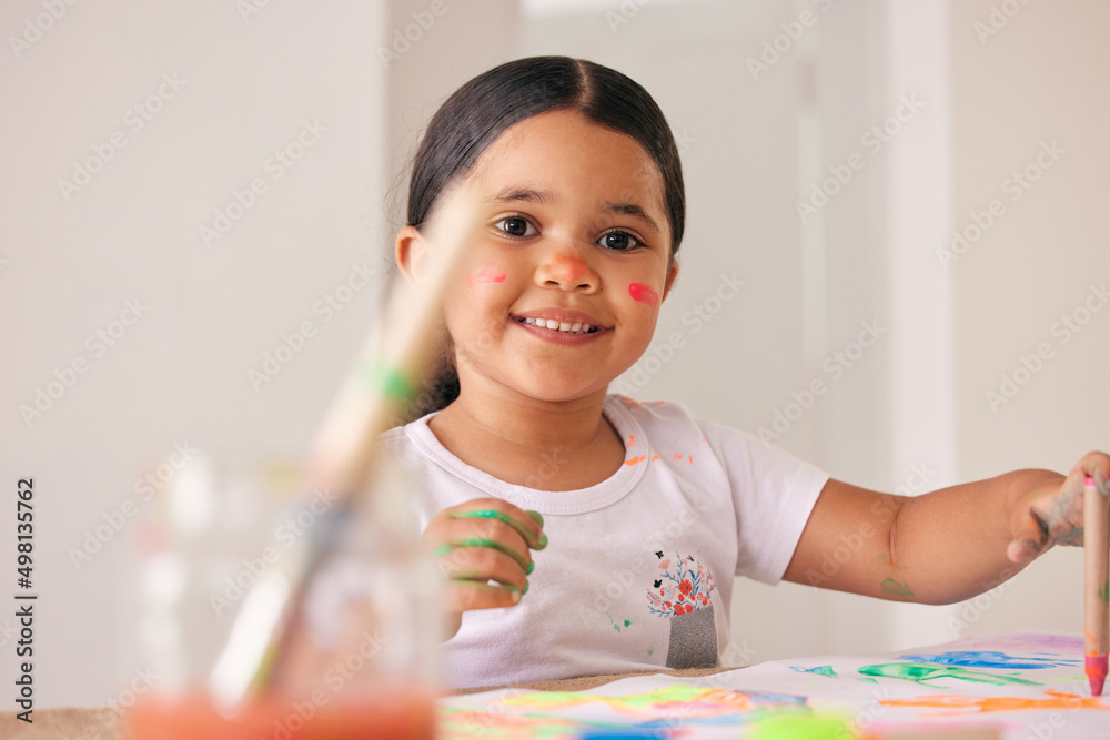 Let them express themselves through art. Shot of an adorable little girl painting while sitting at a