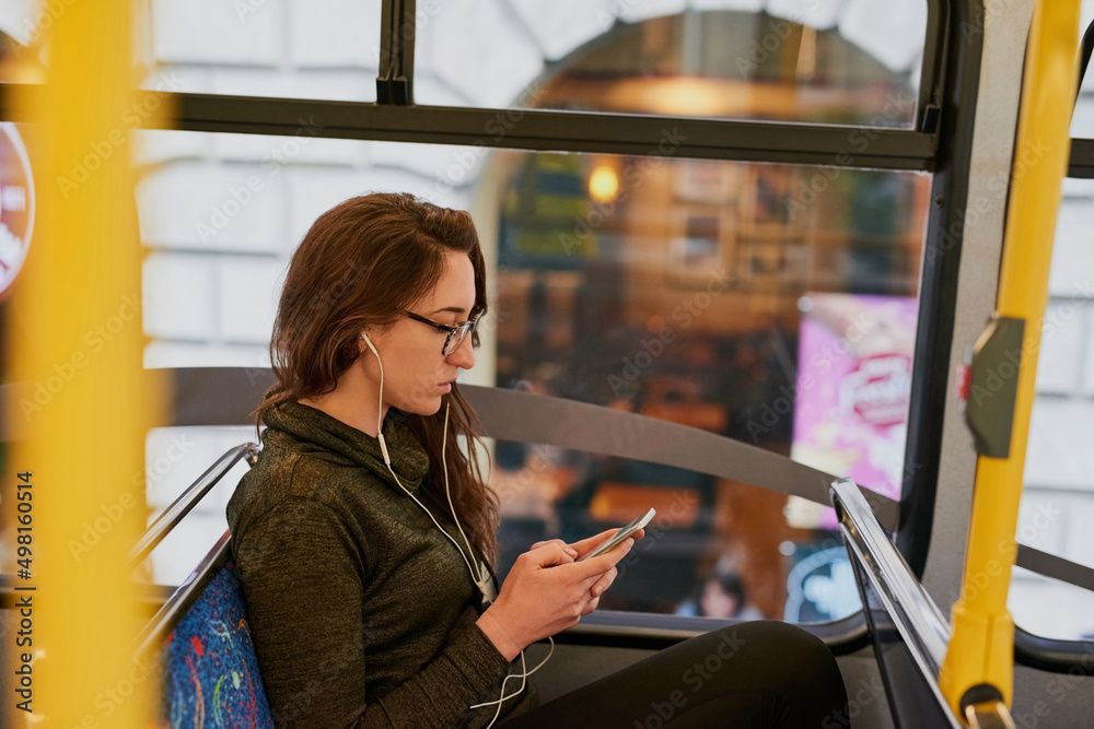 She takes the bus everywhere. High angle shot of an attractive young woman listening to music while 