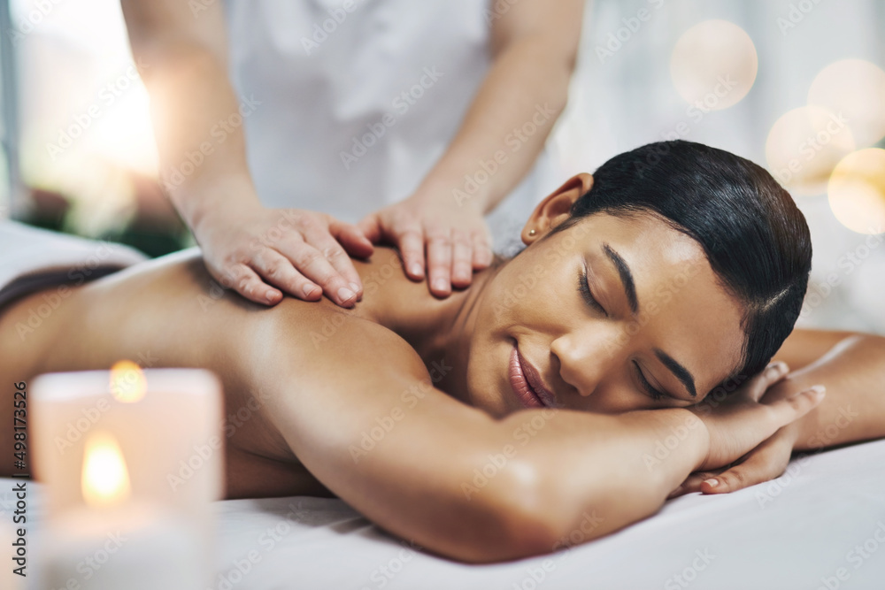 The highlight of my day. Shot of a relaxed an cheerful young woman getting a massage indoors at a sp