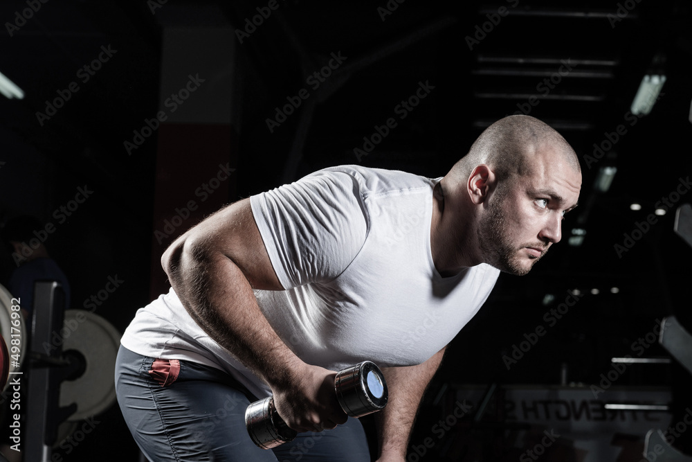 Male bodybuilder engaged with dumbbells in the gym