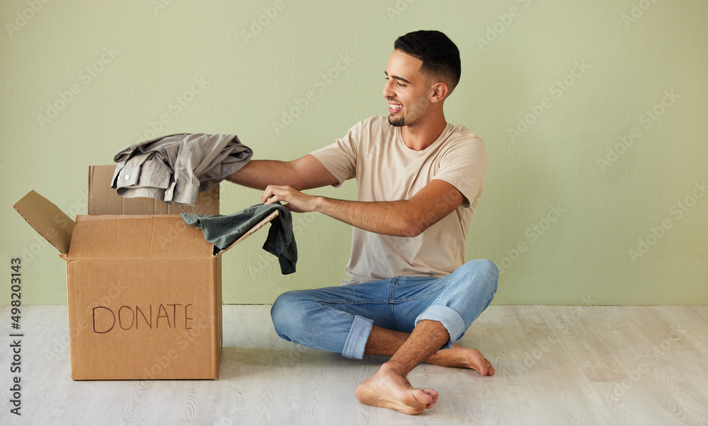 Donating some of my old clothes. Shot of a young man putting clothes into a donation box at home.