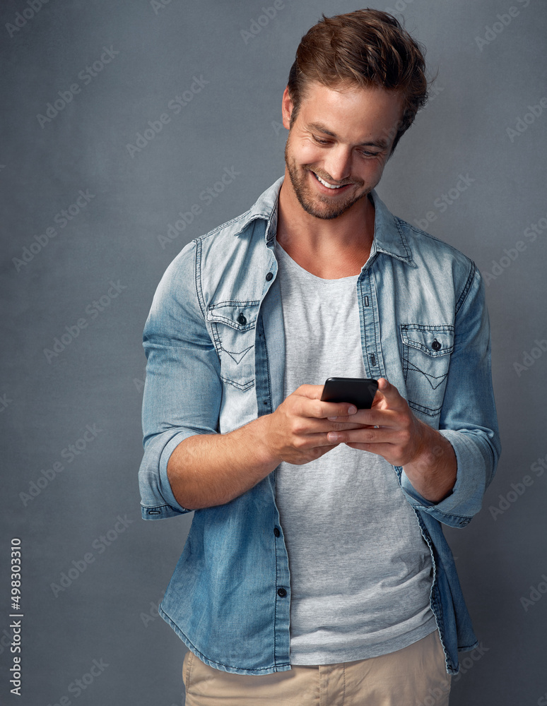 Connected to his friends whenever, wherever. Shot of a happy young man using his smartphone while st