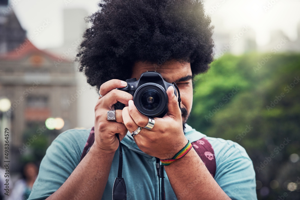 Capturing the city his way. Shot of a young man taking pictures with a camera in the city.