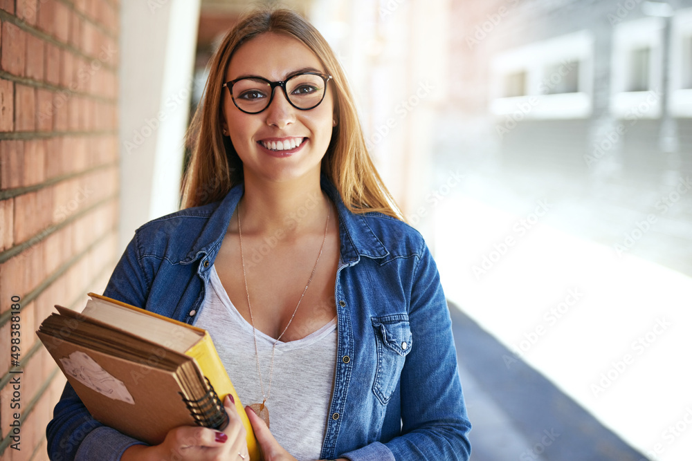 热爱大学生活。一位面带微笑的女大学生站在校园里背着的肖像