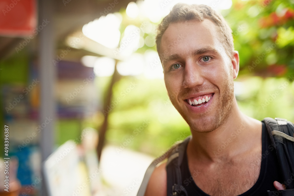 Loving backpacking life. Portrait of a smiling young man wearing a backpack traveling in Thailand.