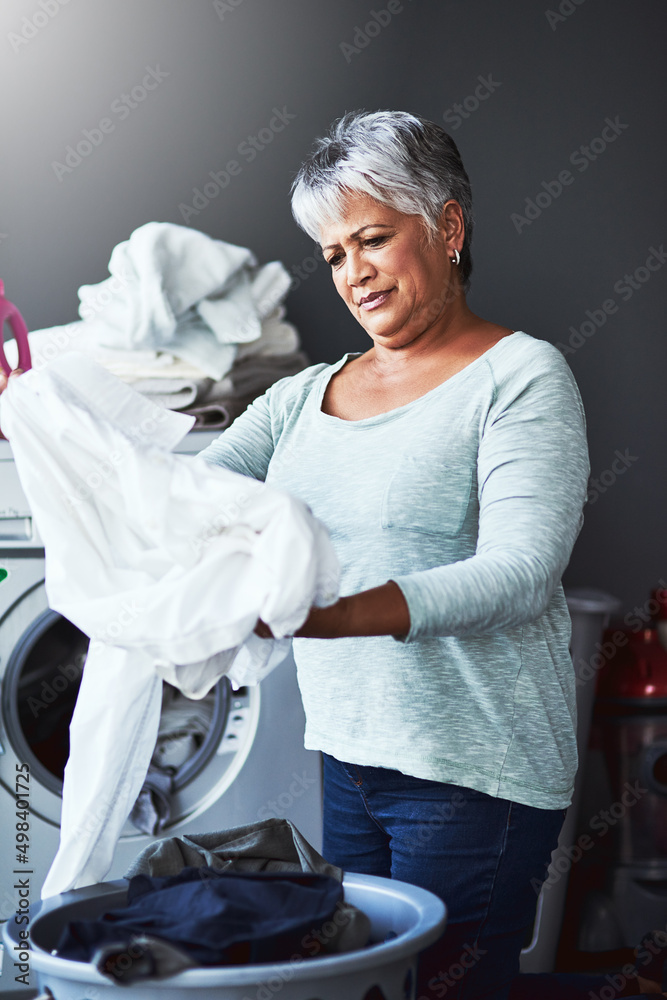 也许它需要再洗一轮。一个成熟女人在家洗衣服的镜头。