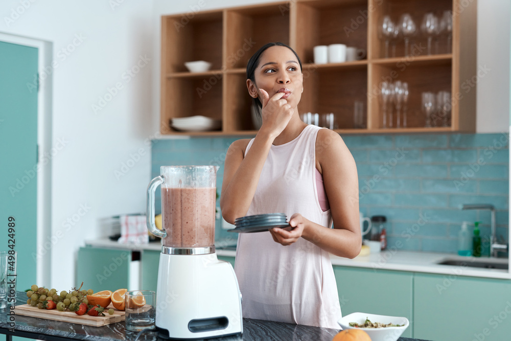 Delicious. Cropped shot of an attractive young woman making smoothies in her kitchen at home.