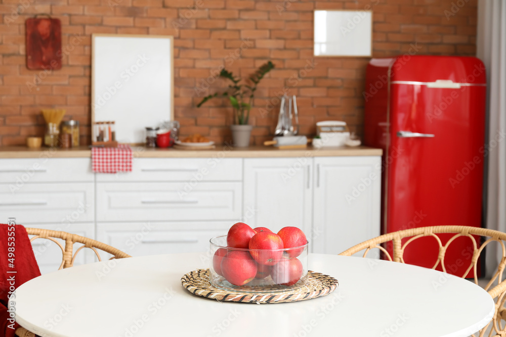 Bowl with fresh apples on table in kitchen