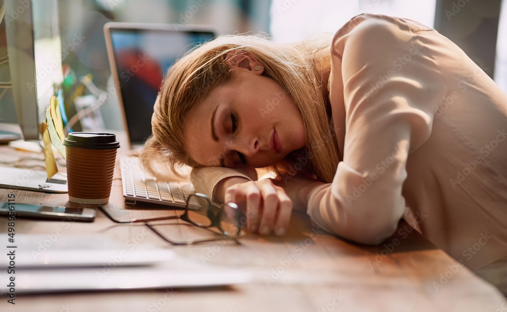 Long hours are taking their toll. Shot of an exhausted young businesswoman asleep at her desk in an 