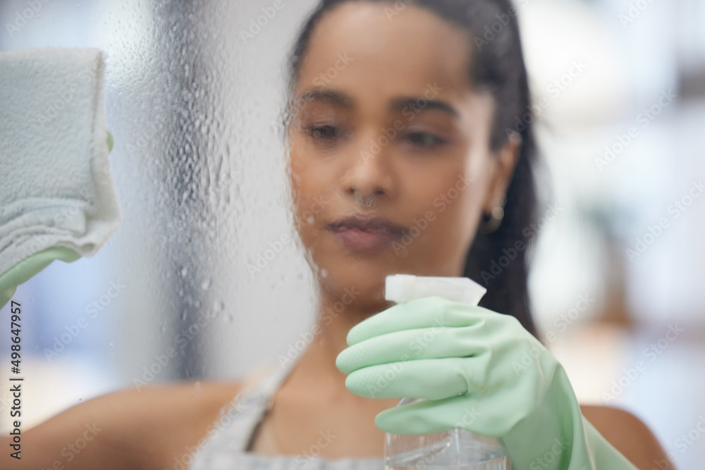 Have to get these windows clean. Shot of a young woman cleaning windows at home.