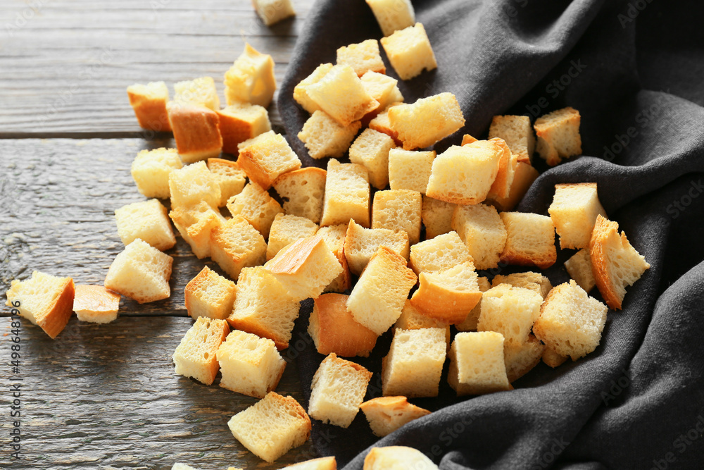 Many crunchy croutons on wooden table