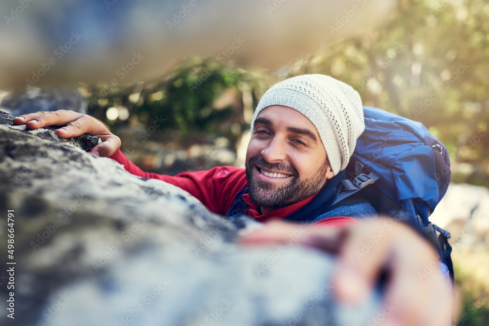 Onwards and upwards. Portrait of a happy hiker climbing over rocks on a mountain trail.