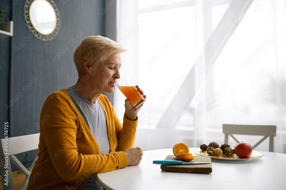 微笑的白发女人拿着装有果汁的杯子