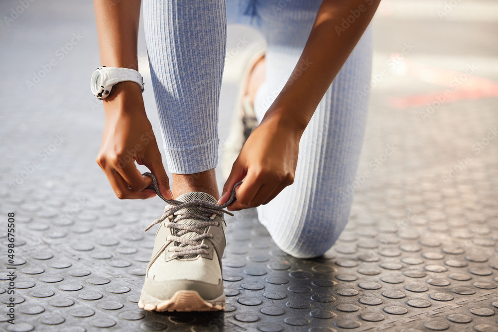 Step into the winners circle. Shot of an unrecognizable woman tying her shoelaces before a workout i