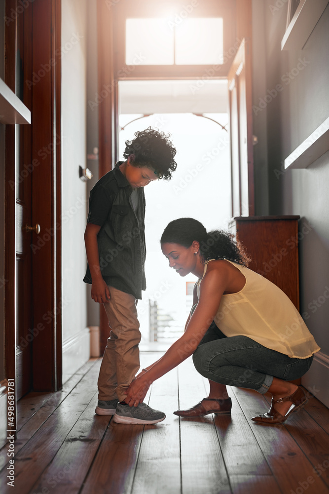 And thats how you tie shoelaces. Shot of a woman tying her sons shoelaces.