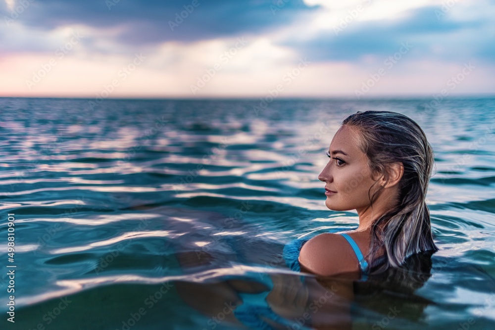 A girl with beautiful facial features looks into an unknown distance while sitting in the estuary