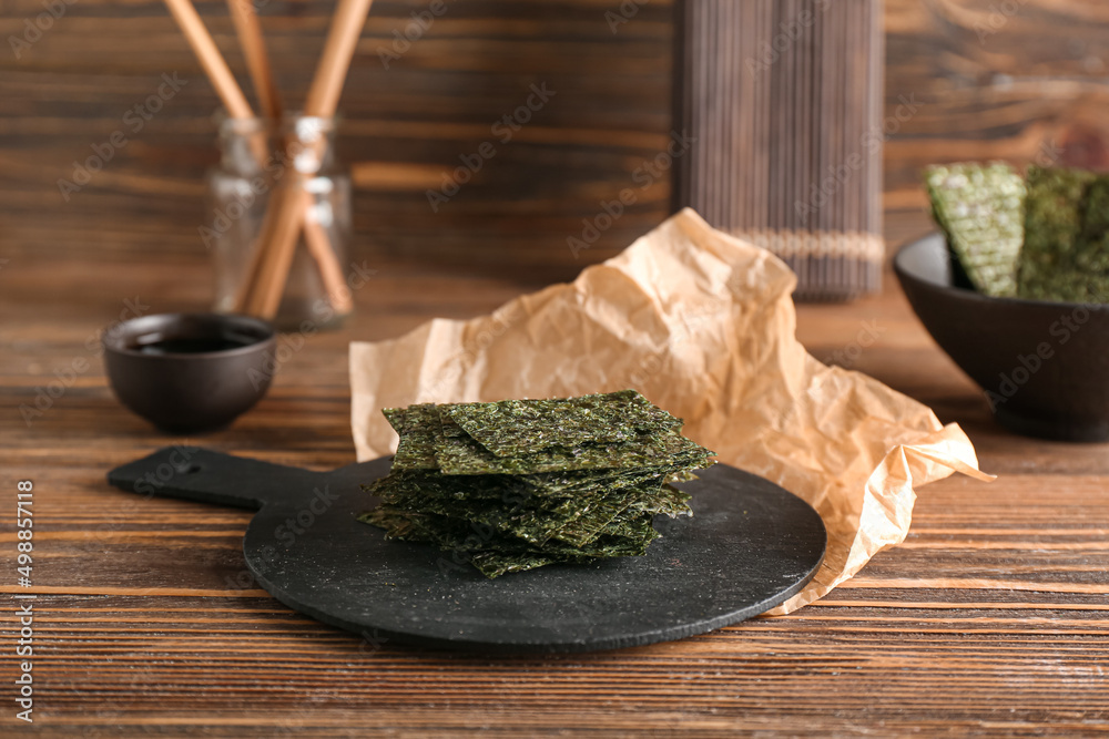 Board of tasty seaweed sheets on wooden background