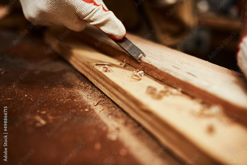 This tool works wonders. Closeup of an unrecognizable carpenter filing down a piece of wood inside o