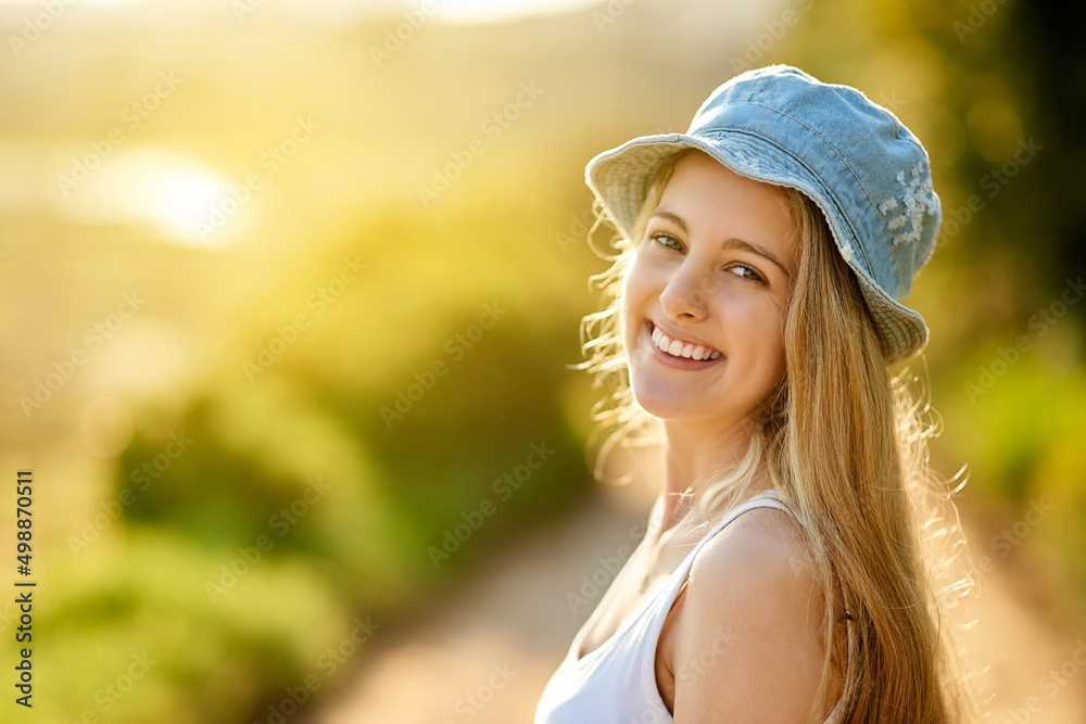 I love being outside. Shot of a young woman on a tree stump out in the countryside.