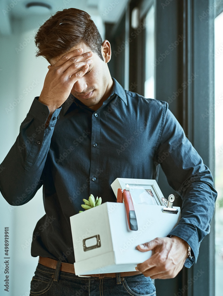 This cant be happening to me. Shot of an unhappy businessman holding his box of belongings after get