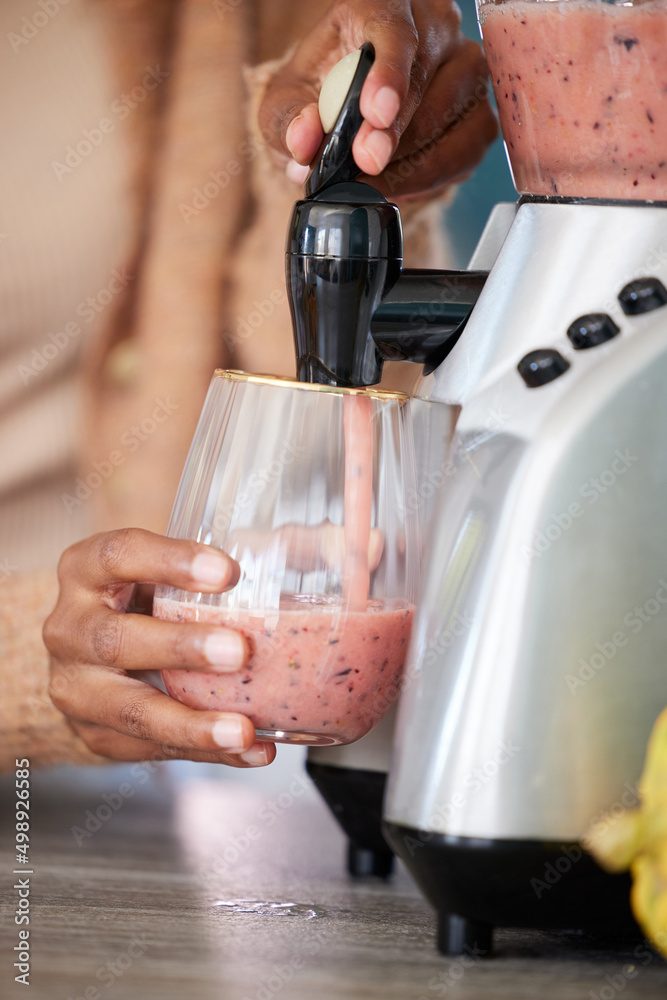 Simply blend and enjoy. Closeup shot of an unrecognisable woman pouring a freshly blended smoothie i