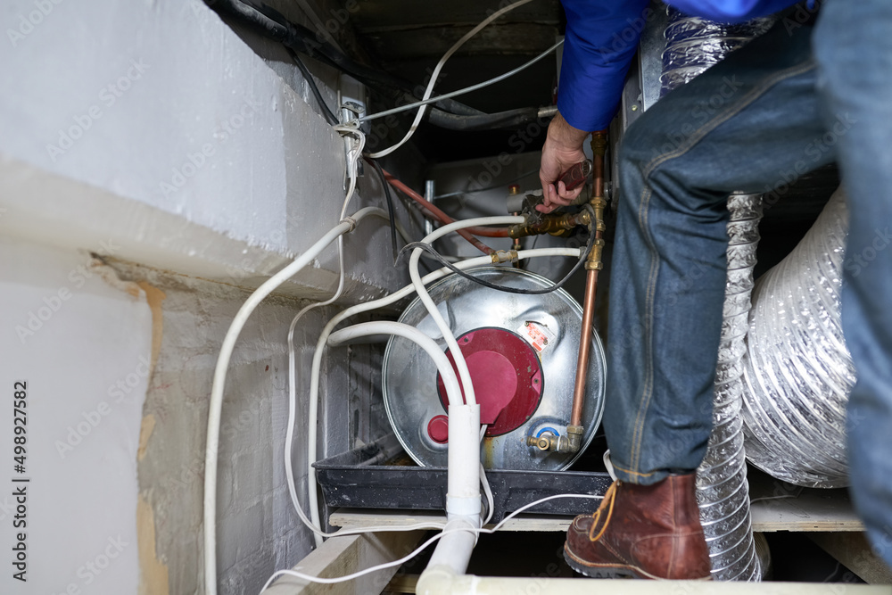 Tracing the faulty pipe to its source. Cropped shot of a handyman repairing a pipe on a water heater