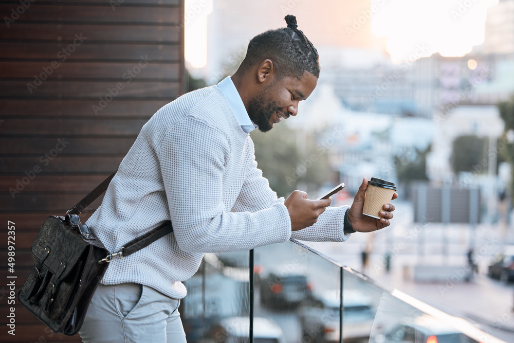 Im out on the balcony. Cropped shot of a handsome young businessman texting while enjoying a takeawa