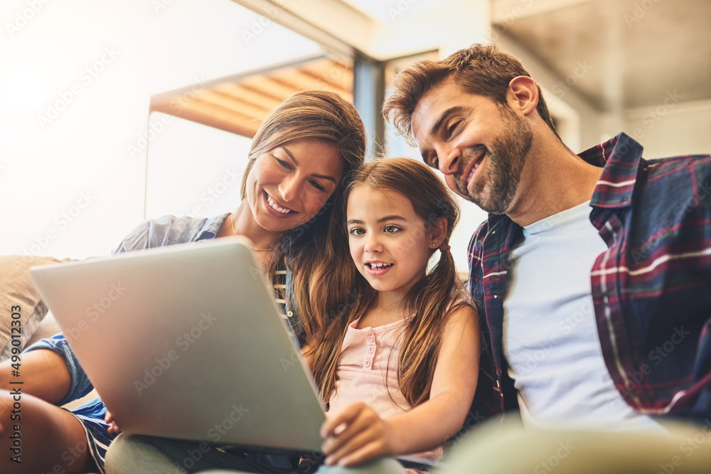 Growing up in a connected world. Shot of a mother and father using a laptop with their daughter on t