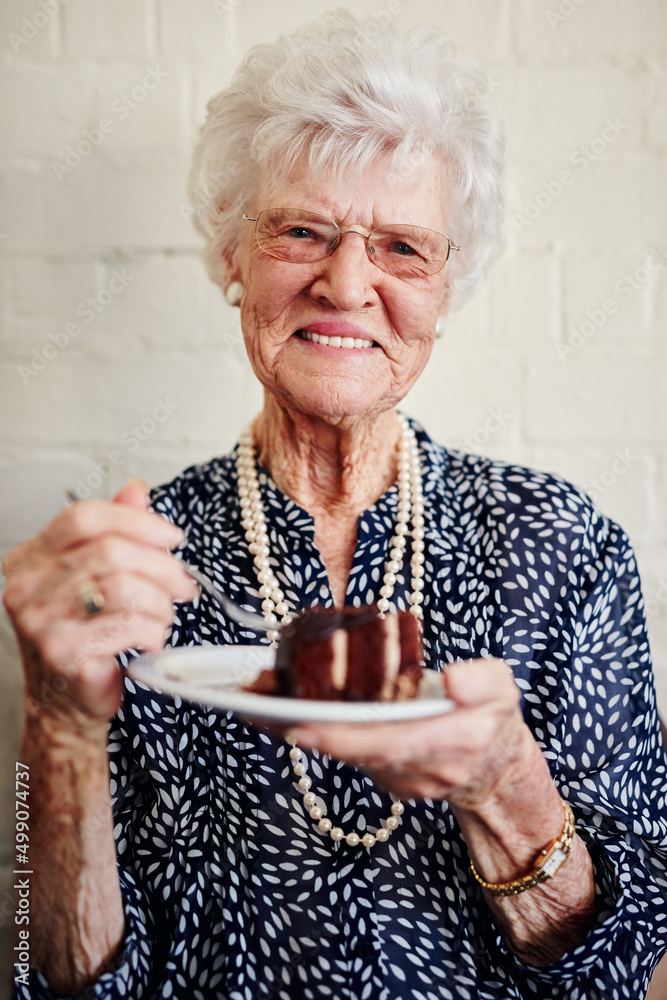 Retirement suits me. Shot of a senior woman eating a slice of cake inside.