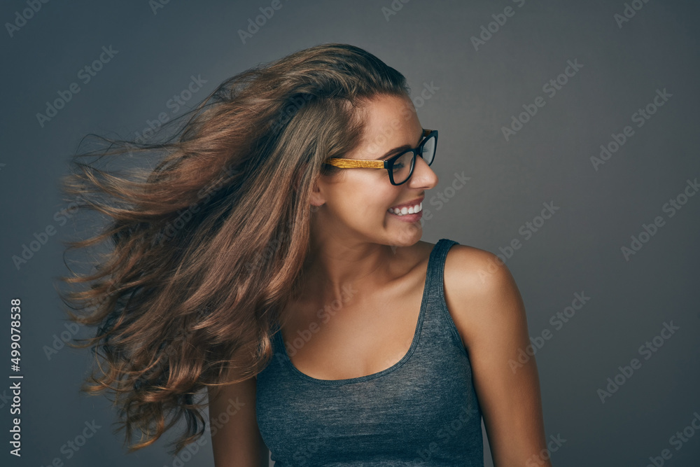 Make every hair flip fabulous. Studio shot of an attractive young woman wearing glasses.