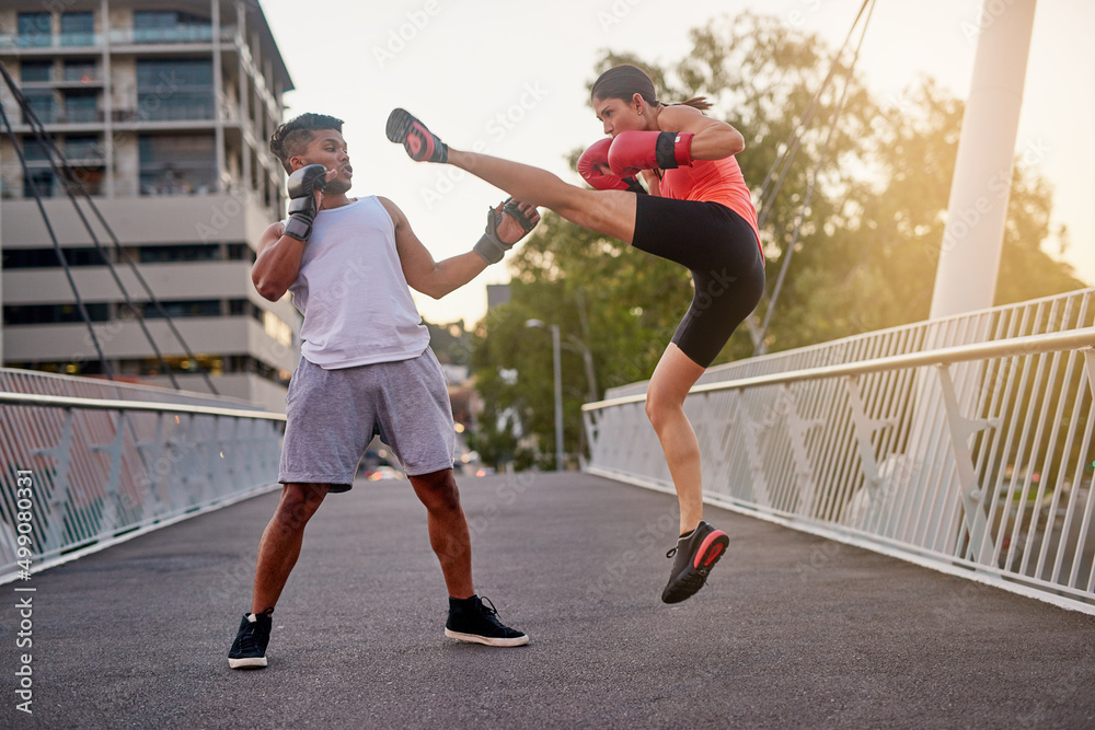 Working on her kicks. Shot of a young couple going through some kickboxing routines outdoors on a br